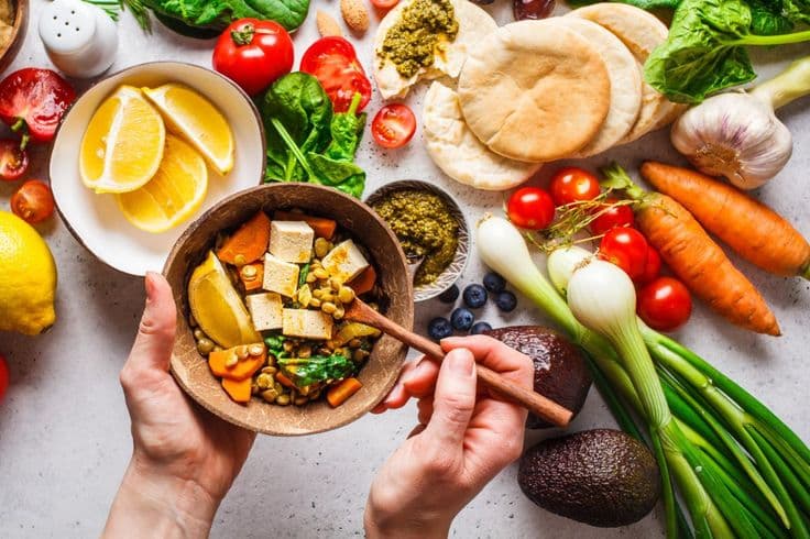 A vibrant plate full of colorful vegetables, fruits, and legumes representing plant-forward eating.